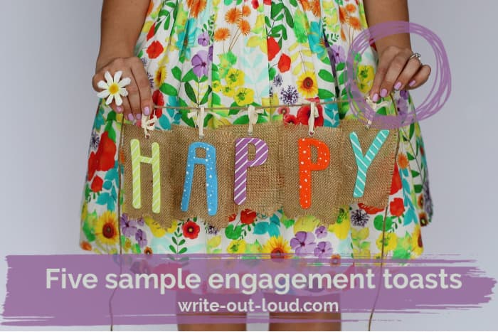 Girl wearing a colorful flowery skirt holding a piece of burlap with the word Happy on it.