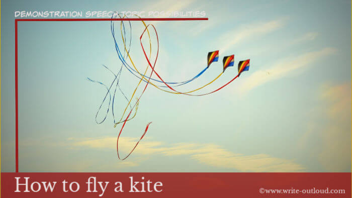 Image: three multi-colored kites against blue sky. Text-Demonstration speech topic-  How to fly a kite.